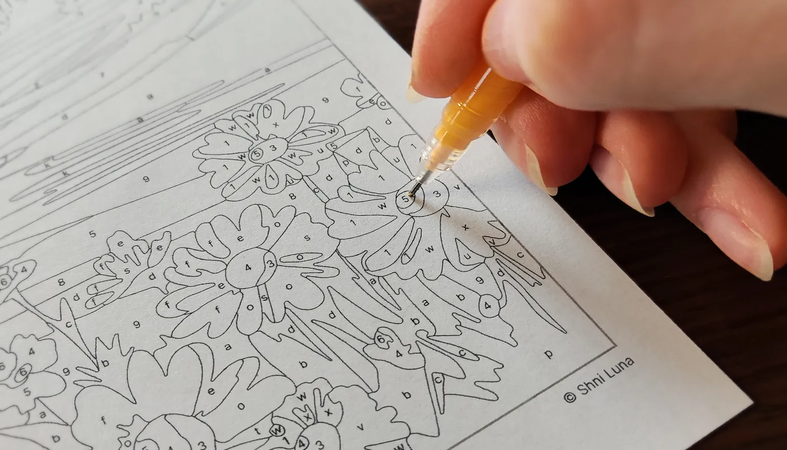 Coloring a printed paint-by-number page with a gel pen