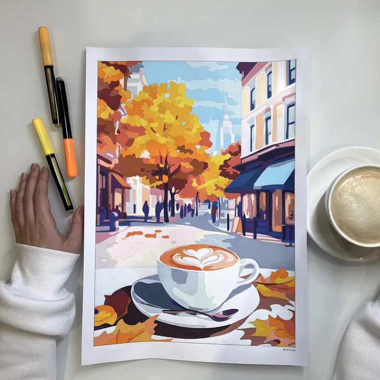 Finished autumn street coloring page with a latte, lying on a desk next to markers and a real cup of coffee