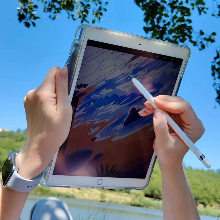 Coloring a landscape paint-by-number page on an iPad outdoors by a river on a sunny day