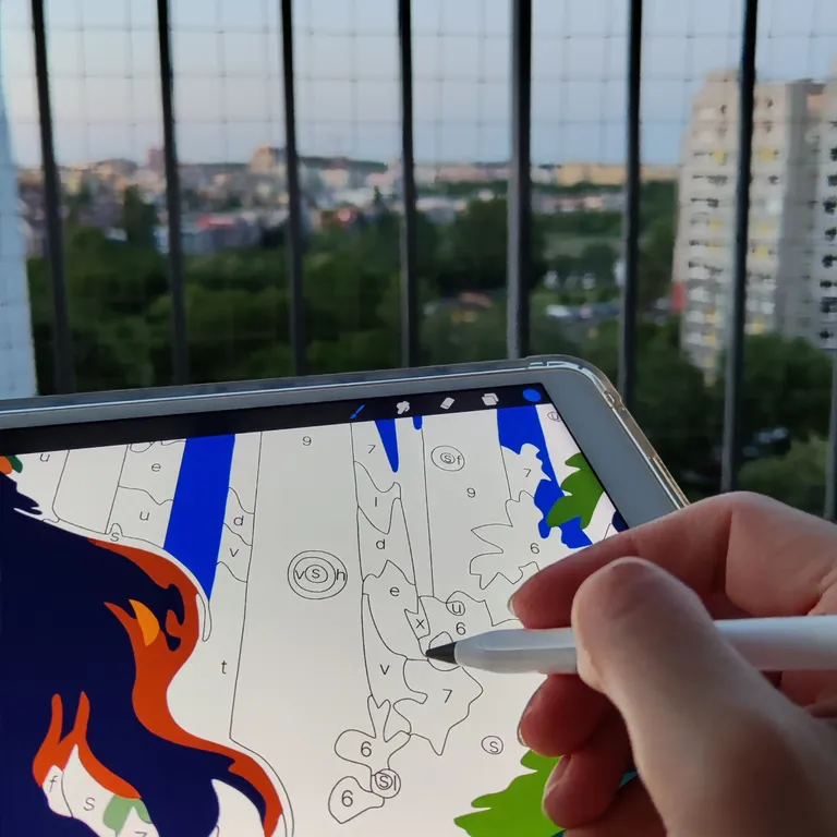 Coloring a paint-by-number page on a tablet on a balcony at sunset