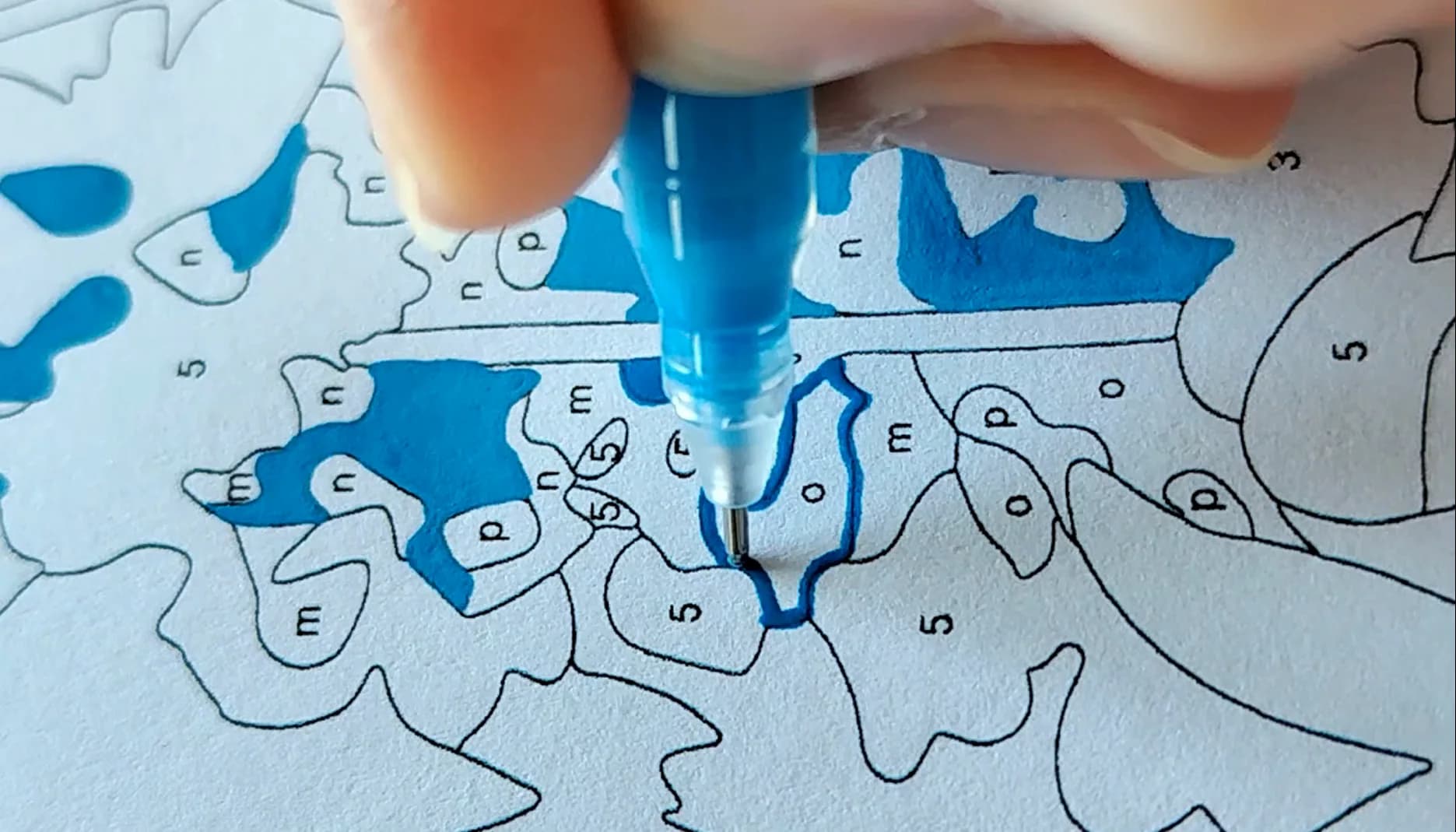 Coloring a printed paint-by-number page with a blue pen