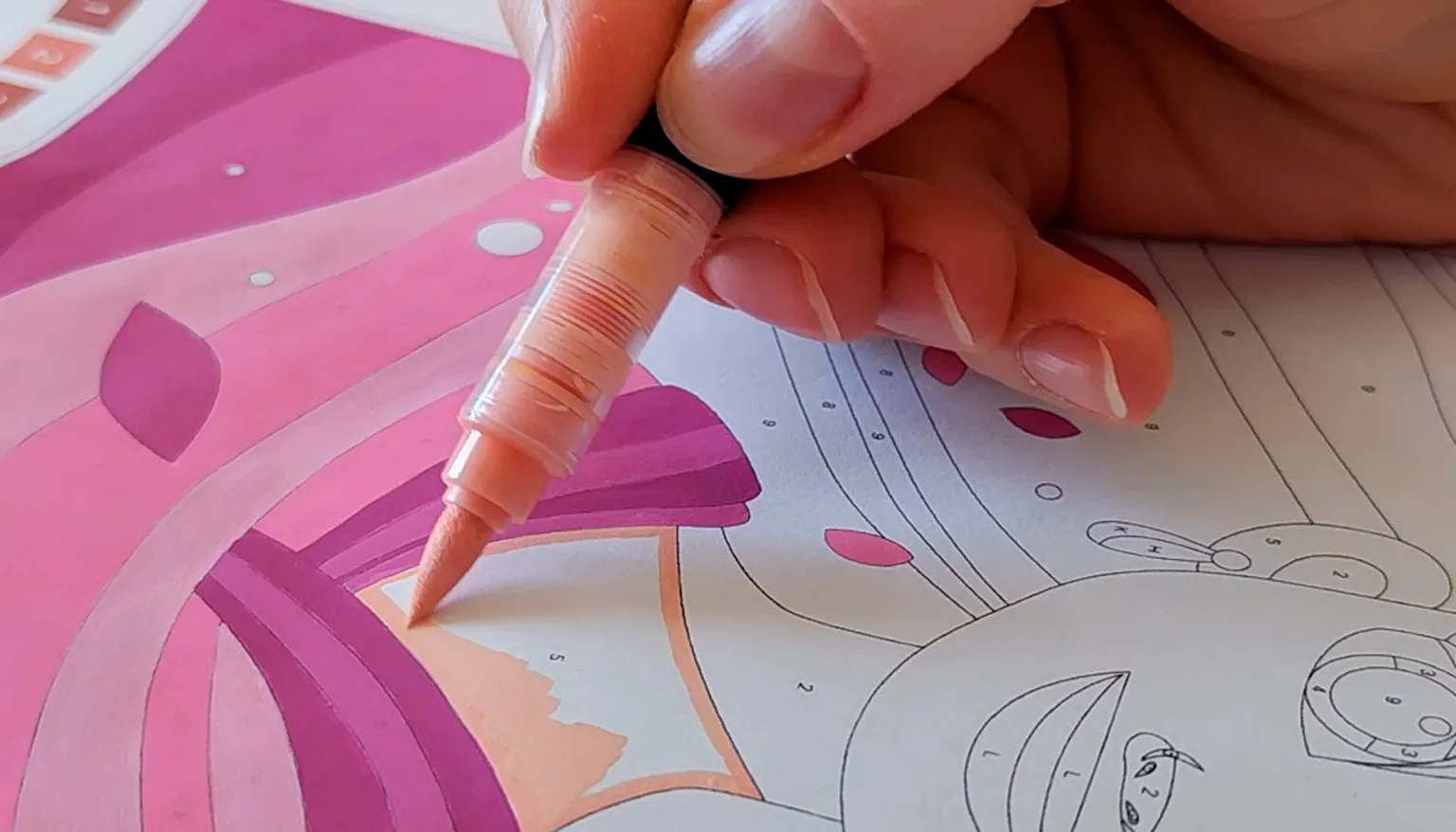 Coloring a printed paint-by-number page with a brush marker